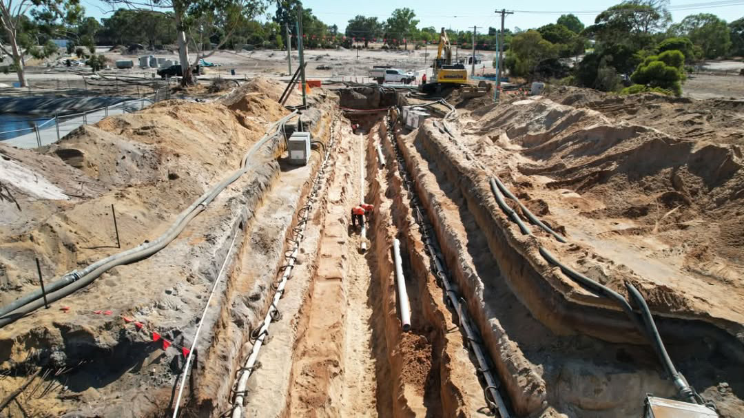 Civil crew managing industrial hose on a wet construction site